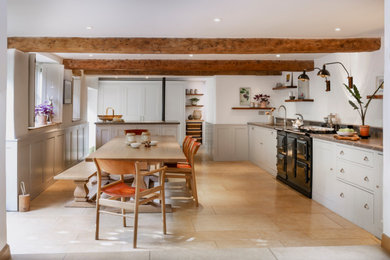 Photo of a farmhouse kitchen/diner in Gloucestershire with shaker cabinets, marble worktops and an island.