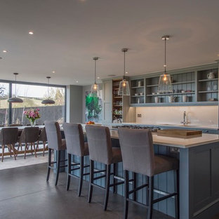 This is an example of a medium sized traditional single-wall kitchen/diner in Other with a double-bowl sink, beaded cabinets, blue cabinets, white splashback, an island and black floors.