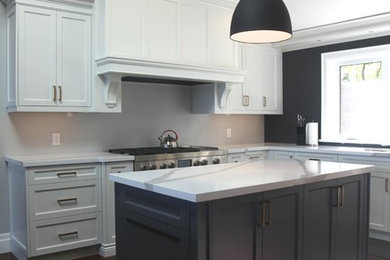 Example of a large transitional u-shaped dark wood floor and brown floor enclosed kitchen design in Toronto with an undermount sink, shaker cabinets, white cabinets, soapstone countertops, stainless steel appliances and two islands