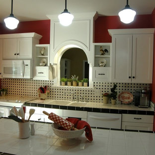 This is an example of a small country single-wall eat-in kitchen in Louisville with a double-bowl sink, shaker cabinets, white cabinets, tile benchtops, multi-coloured splashback, ceramic splashback, white appliances, dark hardwood floors and with island.