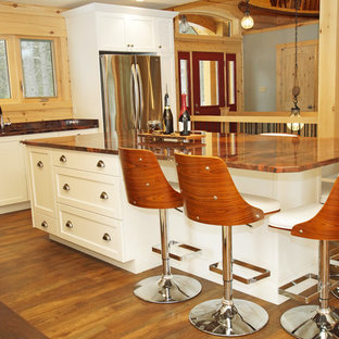 This is an example of a mid-sized country l-shaped eat-in kitchen in Other with an undermount sink, shaker cabinets, white cabinets, granite benchtops, brown splashback, timber splashback, stainless steel appliances, medium hardwood floors, with island, brown floor and orange benchtop.