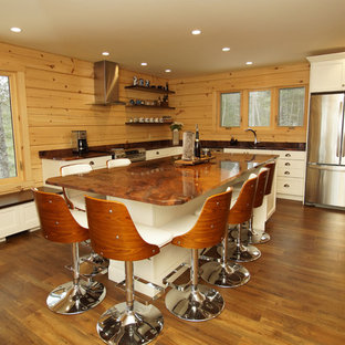 Photo of a mid-sized country l-shaped eat-in kitchen in Other with an undermount sink, shaker cabinets, white cabinets, granite benchtops, brown splashback, timber splashback, stainless steel appliances, medium hardwood floors, with island, brown floor and orange benchtop.