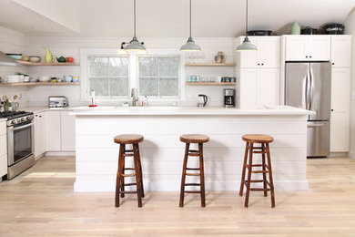 Example of a mid-sized transitional l-shaped light wood floor and beige floor eat-in kitchen design in Boston with an undermount sink, shaker cabinets, white cabinets, quartz countertops, white backsplash, wood backsplash, stainless steel appliances, an island and gray countertops