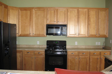 シャーロットにあるトランジショナルスタイルのおしゃれなキッチン (シェーカースタイル扉のキャビネット、淡色木目調キャビネット、黒い調理設備) の写真