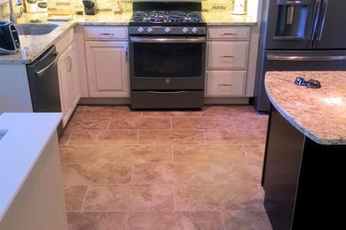 Eat-in kitchen - small transitional galley porcelain tile eat-in kitchen idea in St Louis with an undermount sink, raised-panel cabinets, white cabinets, granite countertops, beige backsplash, stone tile backsplash, colored appliances and an island