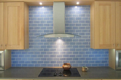 Design ideas for a medium sized traditional kitchen in Phoenix with a belfast sink, shaker cabinets, light wood cabinets, recycled glass countertops, blue splashback, metro tiled splashback and black appliances.
