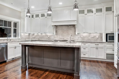 Inspiration for a large transitional u-shaped dark wood floor and brown floor kitchen remodel in Chicago with an undermount sink, recessed-panel cabinets, white cabinets, granite countertops, gray backsplash, stone tile backsplash, stainless steel appliances and an island