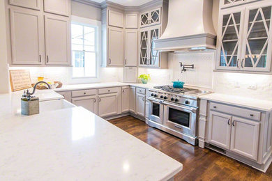 Inspiration for a small transitional u-shaped dark wood floor open concept kitchen remodel in New York with a farmhouse sink, glass-front cabinets, gray cabinets, quartzite countertops, subway tile backsplash, stainless steel appliances and a peninsula