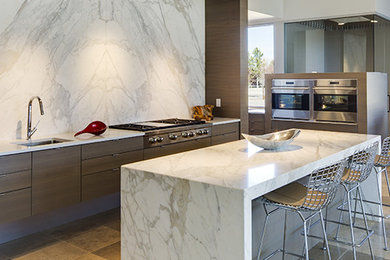 Large trendy single-wall porcelain tile and brown floor eat-in kitchen photo in Austin with an undermount sink, flat-panel cabinets, brown cabinets, marble countertops, gray backsplash, stone slab backsplash, stainless steel appliances, an island and white countertops