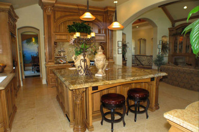 Example of a large classic l-shaped travertine floor enclosed kitchen design in Sacramento with raised-panel cabinets, medium tone wood cabinets, granite countertops, black backsplash, stainless steel appliances and an island