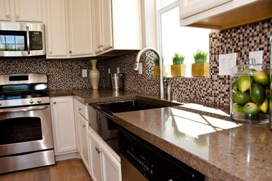 Example of a mid-sized classic l-shaped medium tone wood floor and brown floor kitchen design in Salt Lake City with a farmhouse sink, recessed-panel cabinets, white cabinets, granite countertops, multicolored backsplash, mosaic tile backsplash, stainless steel appliances and multicolored countertops