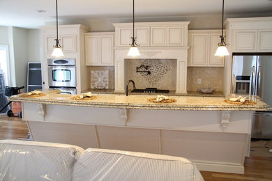 Imagen de cocina grande con armarios con paneles empotrados, encimera de granito, electrodomésticos de acero inoxidable y una isla