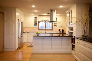 Mid-sized elegant u-shaped light wood floor eat-in kitchen photo in Minneapolis with an undermount sink, raised-panel cabinets, white cabinets, granite countertops, white backsplash, ceramic backsplash, stainless steel appliances and a peninsula