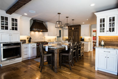 Example of a large transitional l-shaped light wood floor eat-in kitchen design in New York with a farmhouse sink, shaker cabinets, white cabinets, quartzite countertops, beige backsplash, ceramic backsplash, paneled appliances and an island