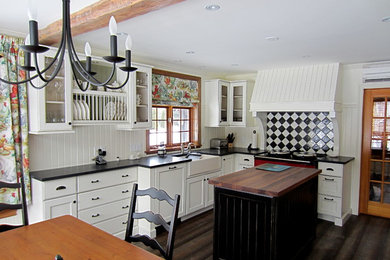 Example of a mid-sized farmhouse galley medium tone wood floor enclosed kitchen design in Montreal with a farmhouse sink, shaker cabinets, white cabinets, marble countertops, white backsplash, stainless steel appliances and an island