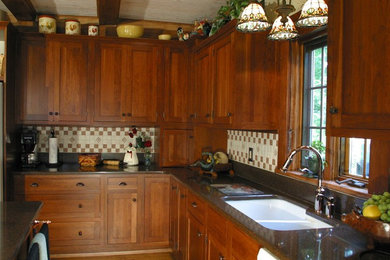 Mid-sized mountain style l-shaped medium tone wood floor and brown floor kitchen photo in Cleveland with a double-bowl sink, shaker cabinets, dark wood cabinets, granite countertops, multicolored backsplash, ceramic backsplash and an island