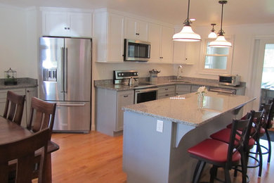 Example of a mid-sized country l-shaped light wood floor eat-in kitchen design in Providence with an undermount sink, shaker cabinets, gray cabinets, granite countertops, stainless steel appliances, an island and white backsplash