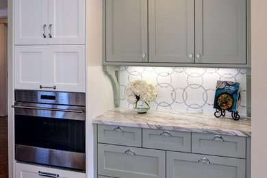 This is an example of a medium sized coastal l-shaped open plan kitchen in San Francisco with a belfast sink, shaker cabinets, white cabinets, marble worktops, multi-coloured splashback, mosaic tiled splashback, stainless steel appliances, medium hardwood flooring and a breakfast bar.