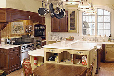 Example of a large classic l-shaped ceramic tile kitchen design in Philadelphia with a farmhouse sink, shaker cabinets, medium tone wood cabinets, solid surface countertops, beige backsplash, ceramic backsplash, stainless steel appliances and an island