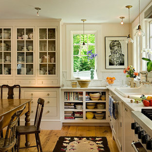 Photo of a traditional eat-in kitchen in Burlington with a drop-in sink, glass-front cabinets, beige cabinets, white splashback, stone slab splashback and stainless steel appliances.