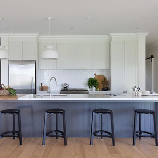 Design ideas for a large country galley eat-in kitchen in Wollongong with white cabinets, quartz benchtops, white splashback, ceramic splashback, stainless steel appliances, with island, white benchtop, an undermount sink, recessed-panel cabinets, medium hardwood floors and beige floor.