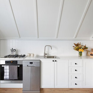 Design ideas for a mid-sized country l-shaped kitchen in Wollongong with white cabinets, quartz benchtops, white splashback, ceramic splashback, stainless steel appliances, white benchtop, a drop-in sink, shaker cabinets and no island.