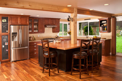 シアトルにある高級なトラディショナルスタイルのおしゃれなキッチン (アンダーカウンターシンク、シェーカースタイル扉のキャビネット、中間色木目調キャビネット、木材カウンター、ベージュキッチンパネル、サブウェイタイルのキッチンパネル、シルバーの調理設備、無垢フローリング) の写真
