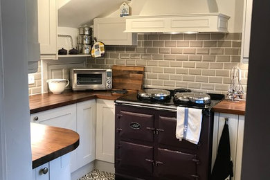 Inspiration for a small traditional u-shaped kitchen in Sussex with white cabinets, grey splashback, metro tiled splashback, brown worktops, shaker cabinets, wood worktops, coloured appliances and multi-coloured floors.