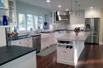Transitional medium tone wood floor eat-in kitchen photo in Chicago with a farmhouse sink, recessed-panel cabinets, white cabinets, granite countertops, white backsplash, subway tile backsplash, stainless steel appliances and an island