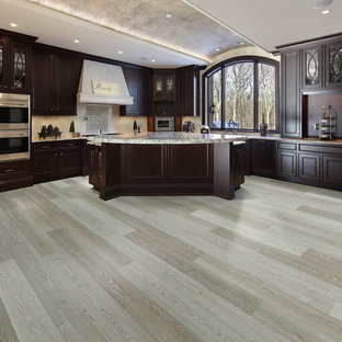Large midcentury l-shaped eat-in kitchen in Los Angeles with a double-bowl sink, recessed-panel cabinets, dark wood cabinets, marble benchtops, beige splashback, ceramic splashback, stainless steel appliances, vinyl floors, with island and grey floor.