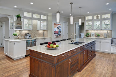 Large elegant galley medium tone wood floor and beige floor kitchen photo in Cleveland with a double-bowl sink, recessed-panel cabinets, dark wood cabinets, quartzite countertops, beige backsplash, subway tile backsplash, stainless steel appliances and an island