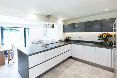 Photo of a medium sized contemporary u-shaped open plan kitchen in Wiltshire with flat-panel cabinets, white cabinets, laminate countertops and grey worktops.