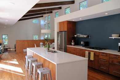 Inredning av ett modernt kök och matrum, med släta luckor, skåp i mellenmörkt trä, rostfria vitvaror, en dubbel diskho, mellanmörkt trägolv och en köksö