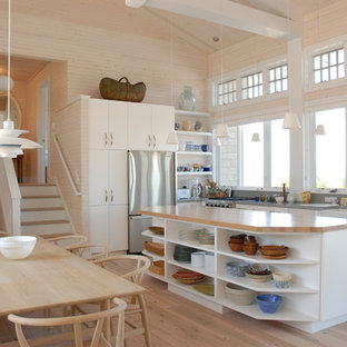 Inspiration for a coastal l-shaped light wood floor open concept kitchen remodel in Other with a farmhouse sink, flat-panel cabinets, white cabinets, stainless steel appliances and an island