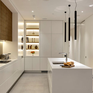 Foto di una grande cucina design con lavello a doppia vasca, ante lisce, ante bianche, top in superficie solida, paraspruzzi beige, paraspruzzi con lastra di vetro, elettrodomestici in acciaio inossidabile, pavimento con piastrelle in ceramica, pavimento grigio e top bianco