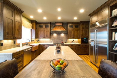 Eat-in kitchen - large rustic l-shaped medium tone wood floor and brown floor eat-in kitchen idea in Denver with a farmhouse sink, recessed-panel cabinets, medium tone wood cabinets, quartz countertops, gray backsplash, porcelain backsplash, stainless steel appliances, an island and beige countertops