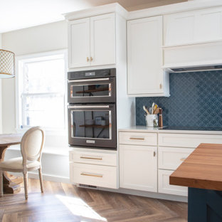 Immagine di un cucina con isola centrale classico con lavello sottopiano, ante in stile shaker, ante bianche, top in quarzo composito, paraspruzzi blu, paraspruzzi con piastrelle in ceramica, elettrodomestici neri, pavimento in vinile e top bianco