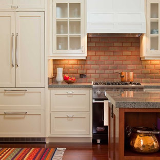 Large traditional enclosed kitchen designs - Enclosed kitchen - large traditional single-wall dark wood floor and brown floor enclosed kitchen idea in San Diego with glass-front cabinets, granite countertops, beige cabinets, red backsplash, brick backsplash, stainless steel appliances and an island