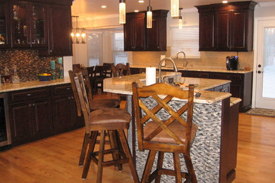 Inspiration for a mid-sized transitional medium tone wood floor eat-in kitchen remodel in Cincinnati with an undermount sink, raised-panel cabinets, dark wood cabinets, granite countertops, gray backsplash, mosaic tile backsplash, stainless steel appliances and an island