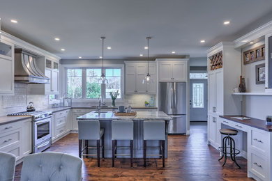 Example of a large transitional medium tone wood floor and brown floor eat-in kitchen design in Toronto with a double-bowl sink, recessed-panel cabinets, white cabinets, quartz countertops, white backsplash, mosaic tile backsplash, stainless steel appliances and an island