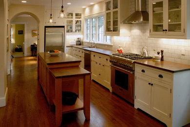 Example of a large tuscan l-shaped medium tone wood floor and brown floor eat-in kitchen design in Cincinnati with an undermount sink, shaker cabinets, white cabinets, granite countertops, white backsplash, ceramic backsplash, stainless steel appliances and an island