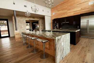 Inspiration for a mid-sized modern medium tone wood floor kitchen remodel in Austin with flat-panel cabinets, granite countertops, gray backsplash and two islands