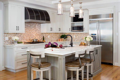 Inspiration for a timeless l-shaped medium tone wood floor kitchen remodel in DC Metro with an undermount sink, shaker cabinets, white cabinets, multicolored backsplash, mosaic tile backsplash, stainless steel appliances and an island