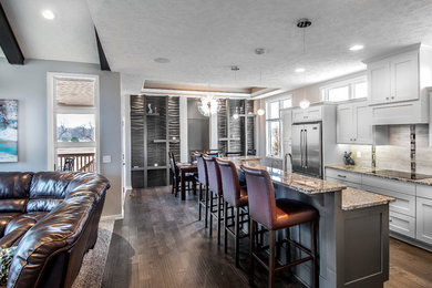 Inspiration for a mid-sized contemporary galley dark wood floor and brown floor eat-in kitchen remodel in Omaha with a drop-in sink, shaker cabinets, white cabinets, gray backsplash, ceramic backsplash, stainless steel appliances and an island