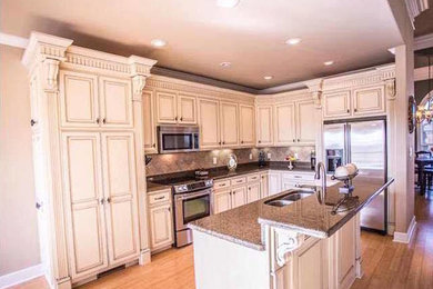 Example of a mid-sized classic l-shaped light wood floor open concept kitchen design in Other with a double-bowl sink, beaded inset cabinets, white cabinets, granite countertops, brown backsplash, stainless steel appliances, an island and ceramic backsplash
