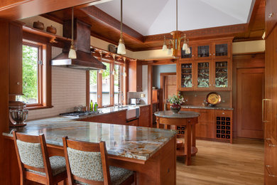 Example of an arts and crafts u-shaped medium tone wood floor and brown floor kitchen design in Minneapolis with a farmhouse sink, flat-panel cabinets, medium tone wood cabinets, gray backsplash, a peninsula and gray countertops