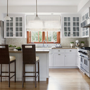 Inspiration for a classic l-shaped kitchen in Los Angeles with stainless steel appliances, a belfast sink, glass-front cabinets, white cabinets, concrete worktops, beige splashback and matchstick tiled splashback.