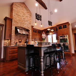 Ejemplo de cocina comedor de estilo americano con fregadero sobremueble, puertas de armario de madera oscura, encimera de granito, electrodomésticos de acero inoxidable y una isla