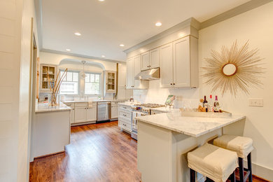Example of a mid-sized arts and crafts l-shaped medium tone wood floor eat-in kitchen design in Miami with an undermount sink, flat-panel cabinets, gray cabinets, marble countertops, white backsplash, ceramic backsplash, stainless steel appliances and a peninsula