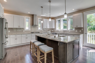 Eat-in kitchen - large craftsman u-shaped bamboo floor and brown floor eat-in kitchen idea in DC Metro with a drop-in sink, raised-panel cabinets, white cabinets, granite countertops, gray backsplash, ceramic backsplash, stainless steel appliances, an island and gray countertops